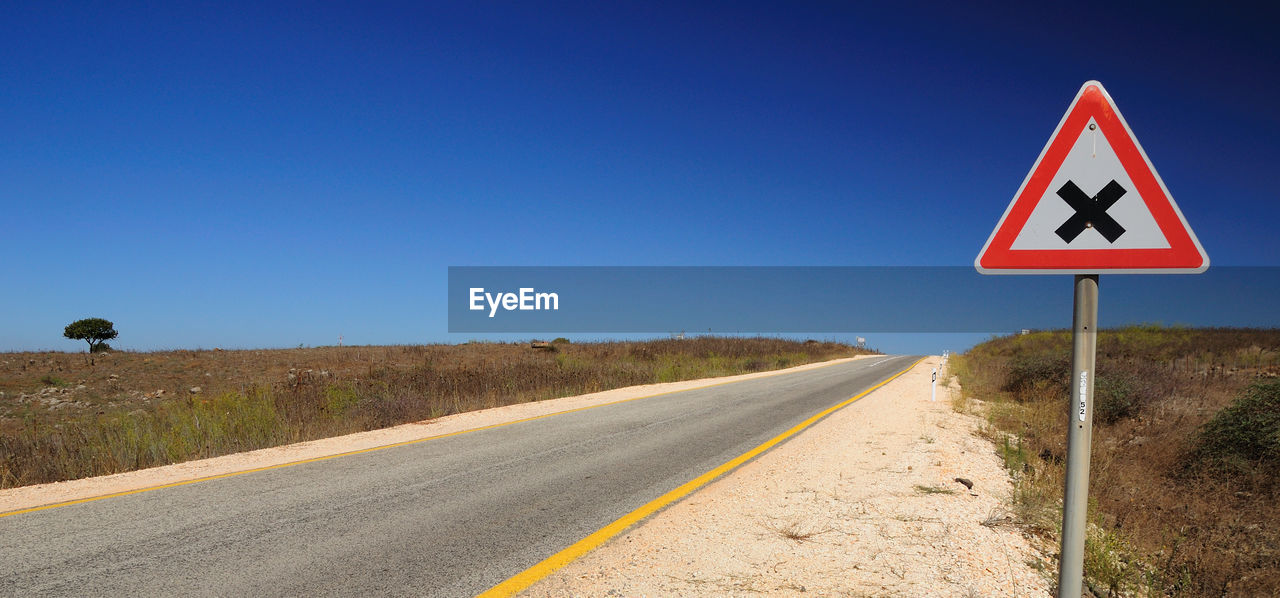 Sign by road against clear blue sky