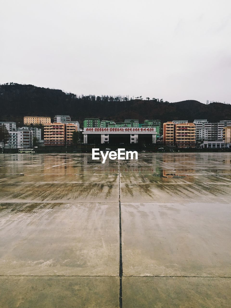 Wet street by buildings against sky