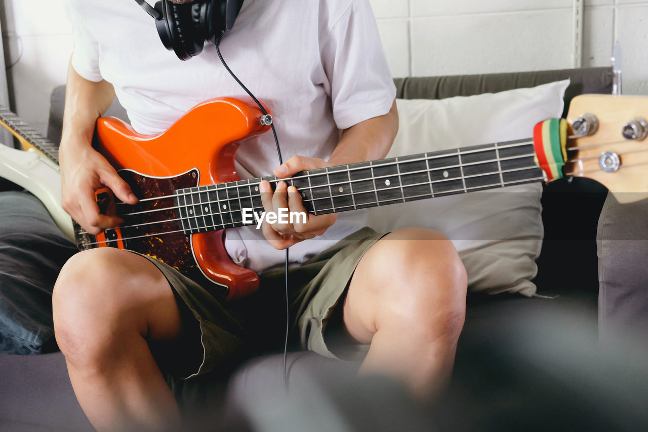 Midsection of man playing guitar