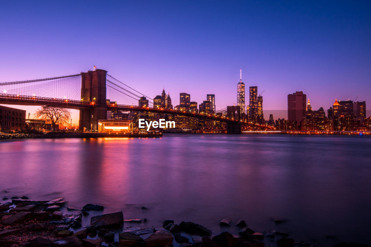 Illuminated city by river at night