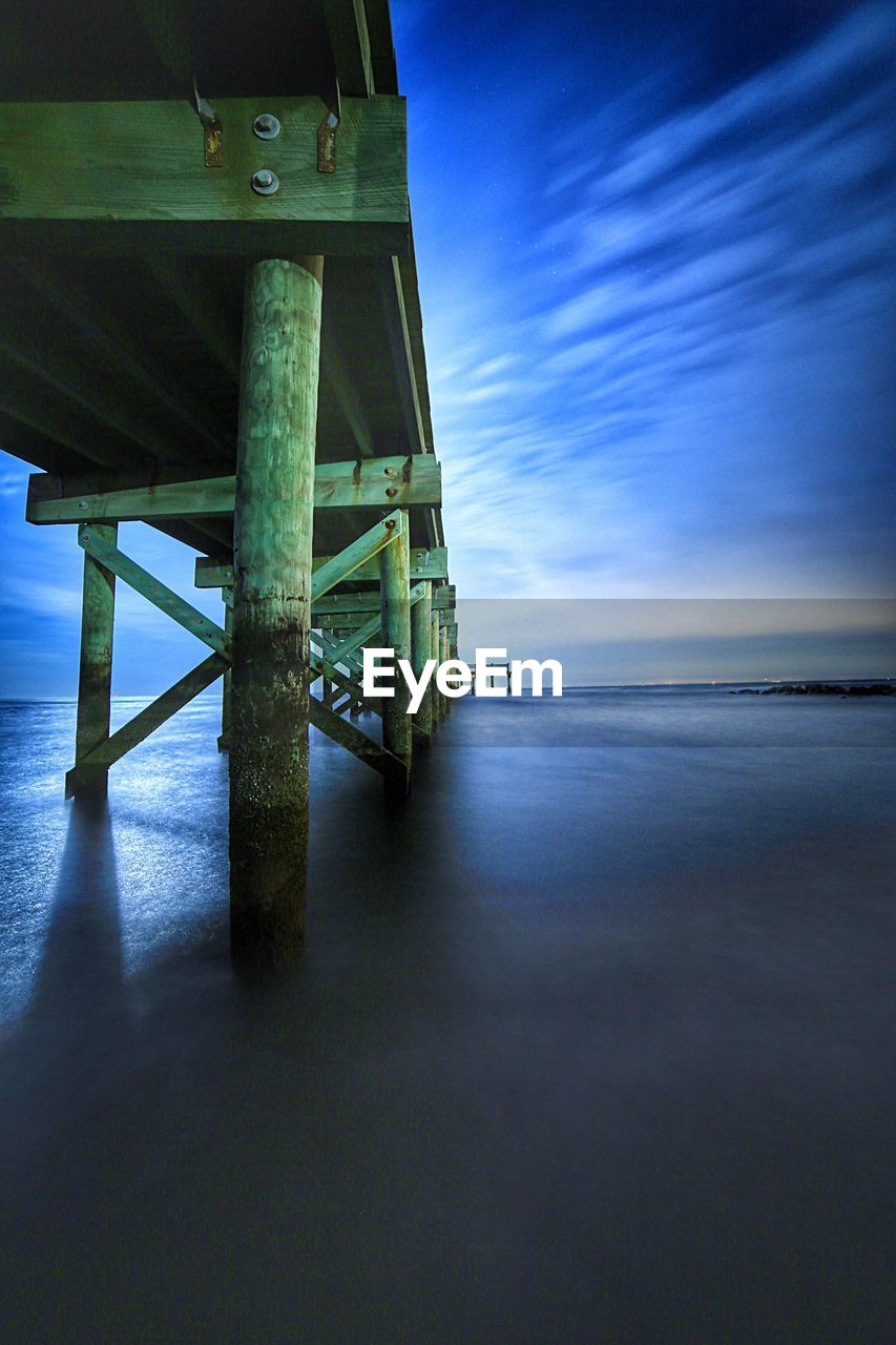 Jetty over sea against cloudy sky