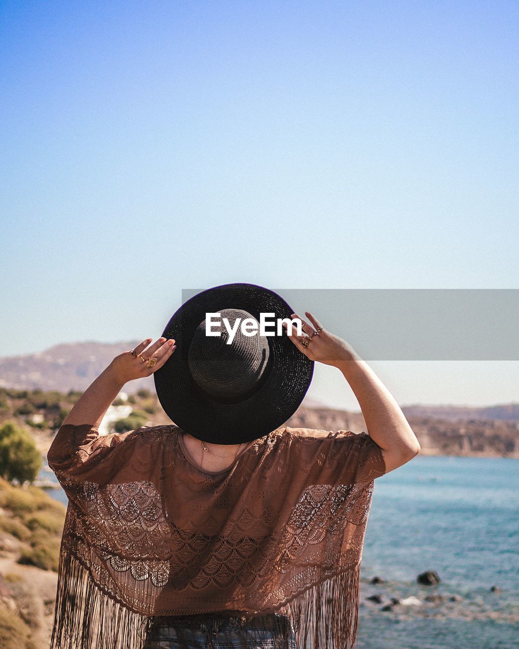 Rear view of woman wearing hat while standing against clear sky