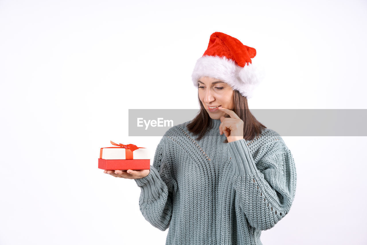 portrait of young woman using smart phone while standing against white background
