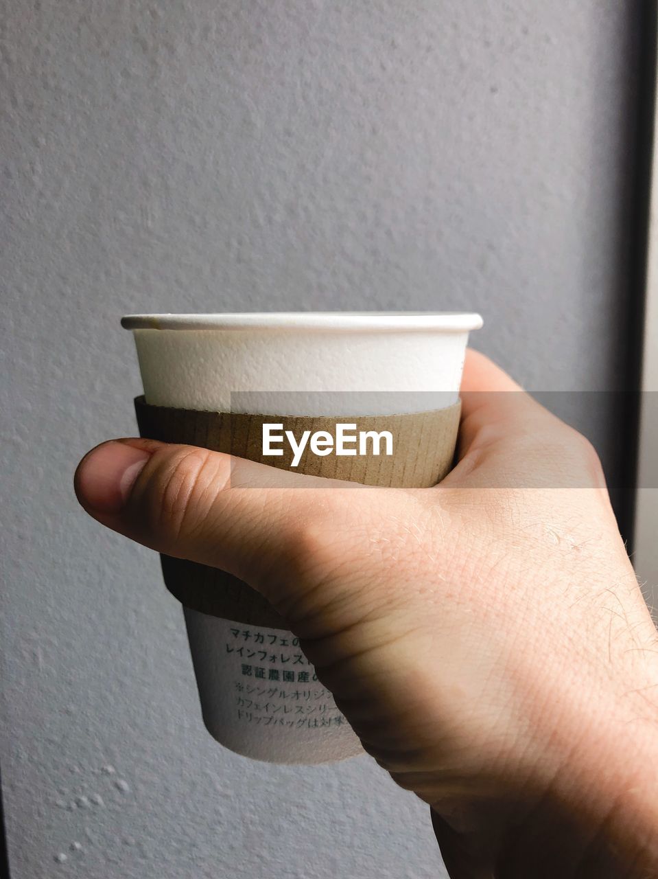 CLOSE-UP OF HAND HOLDING COFFEE CUP