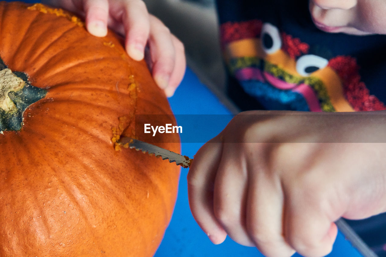 Midsection of girl cutting pumpkin at home