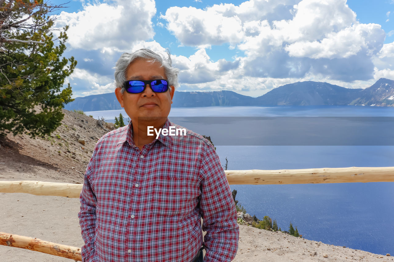 PORTRAIT OF MAN STANDING AGAINST MOUNTAINS