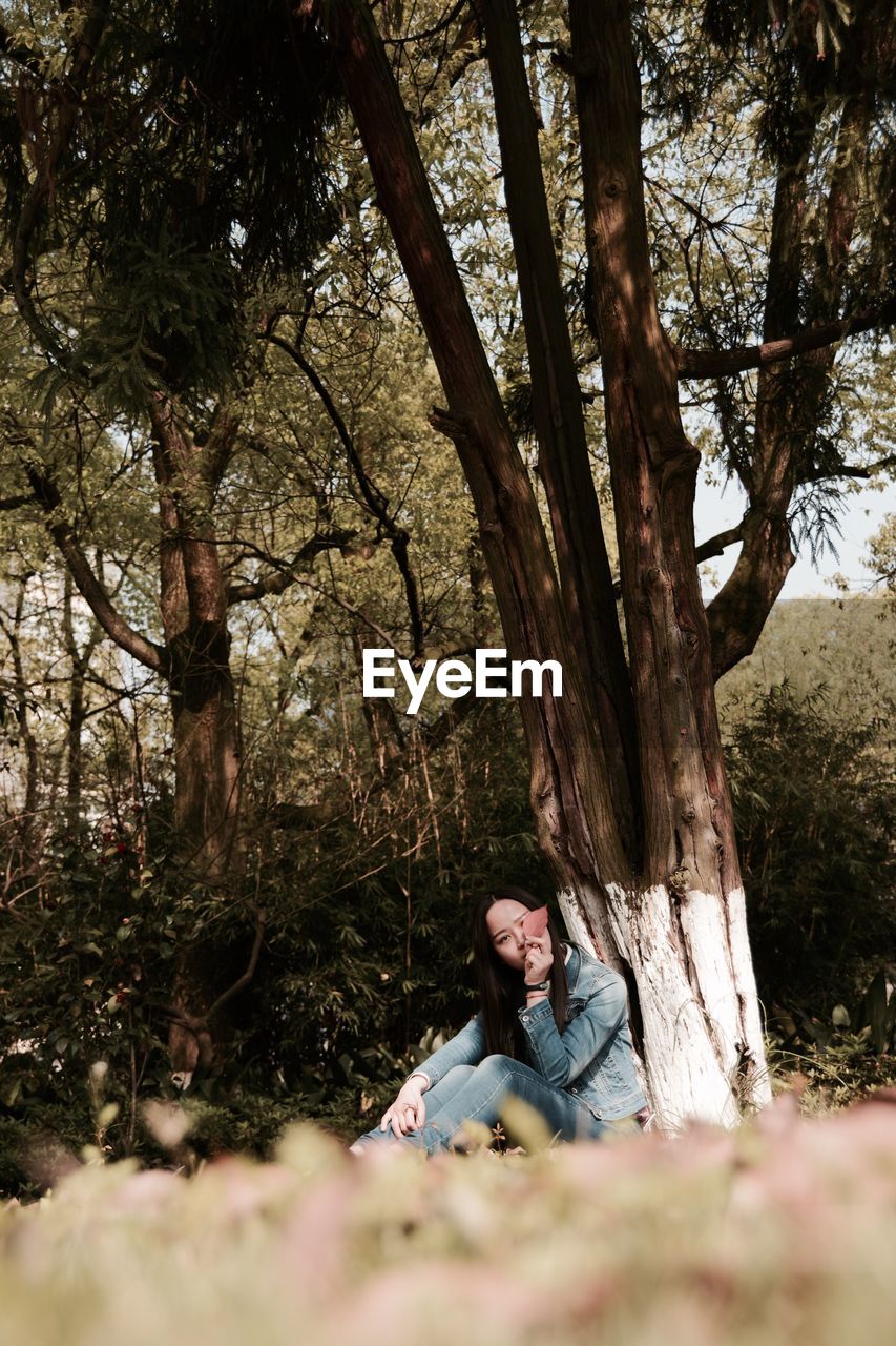 Portrait of woman sitting by tree trunk