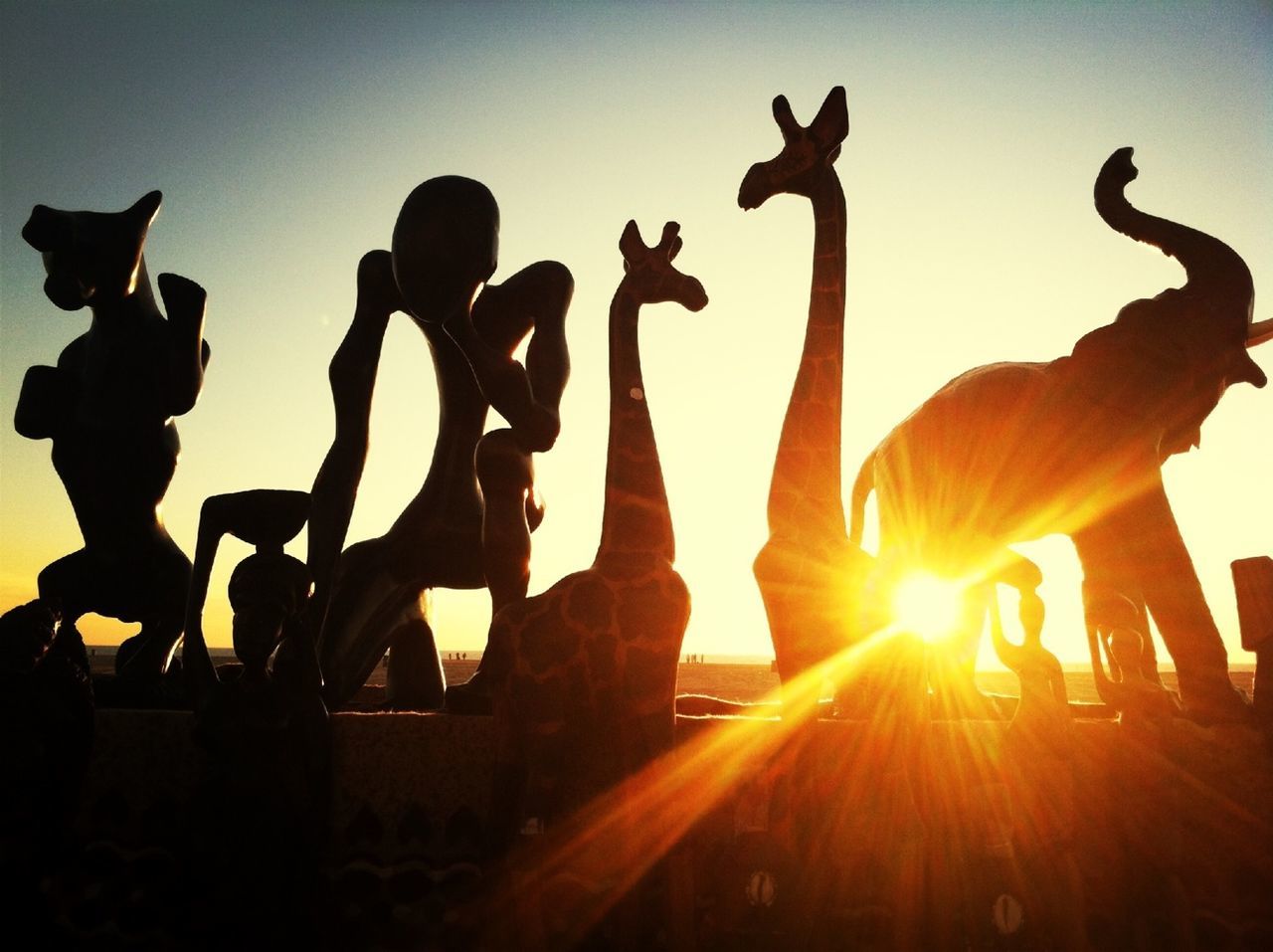 Figurines against clear sky during sunset