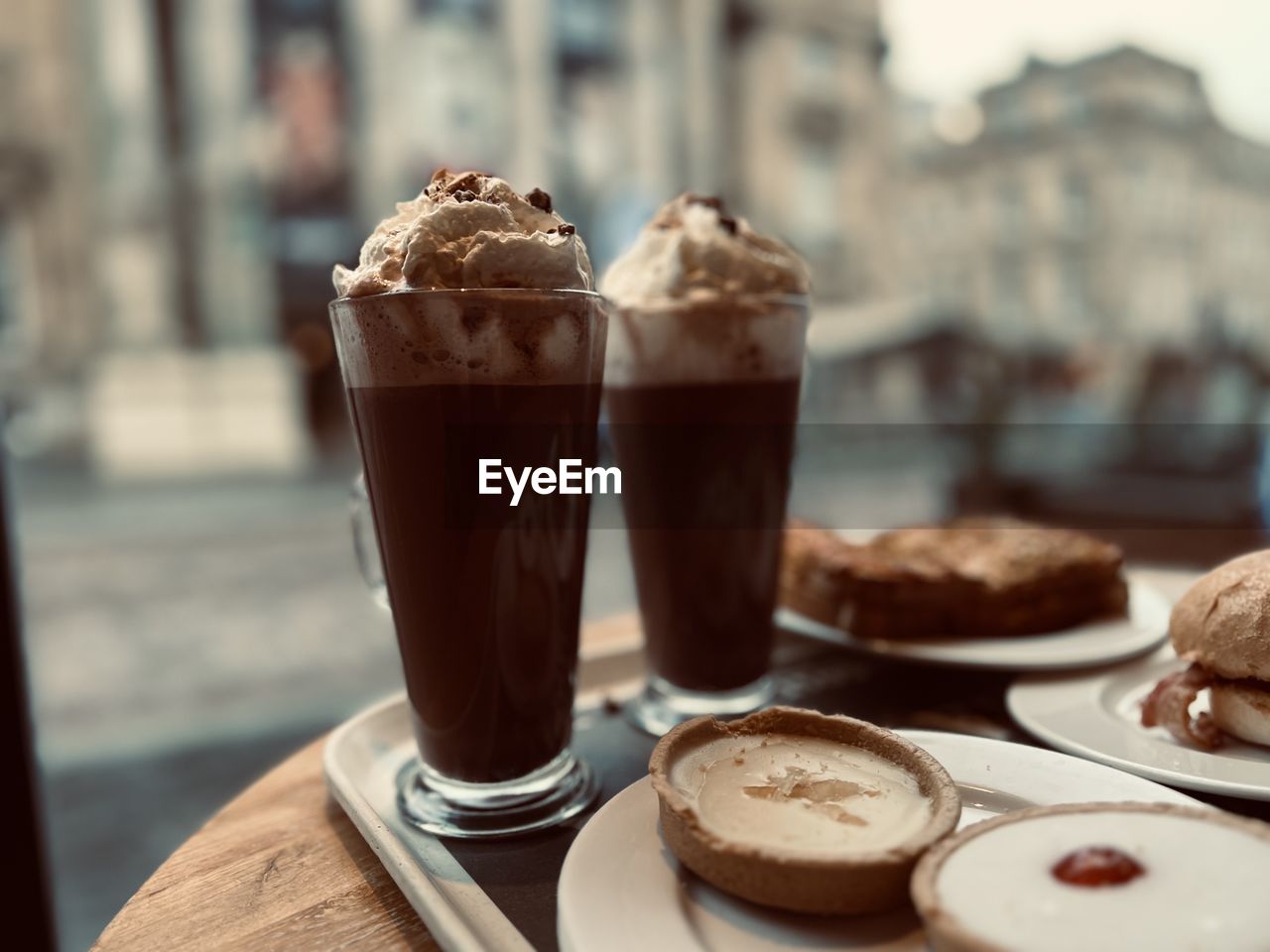 food and drink, food, sweet food, dessert, sweet, drink, chocolate, refreshment, coffee, dairy, soft drink, table, frappé coffee, cafe, temptation, frozen, freshness, focus on foreground, frozen food, hot drink, hot chocolate, ice cream, cream, glass, city, close-up, architecture, drinking glass, household equipment, no people, cup, selective focus, day, whipped, meal, still life