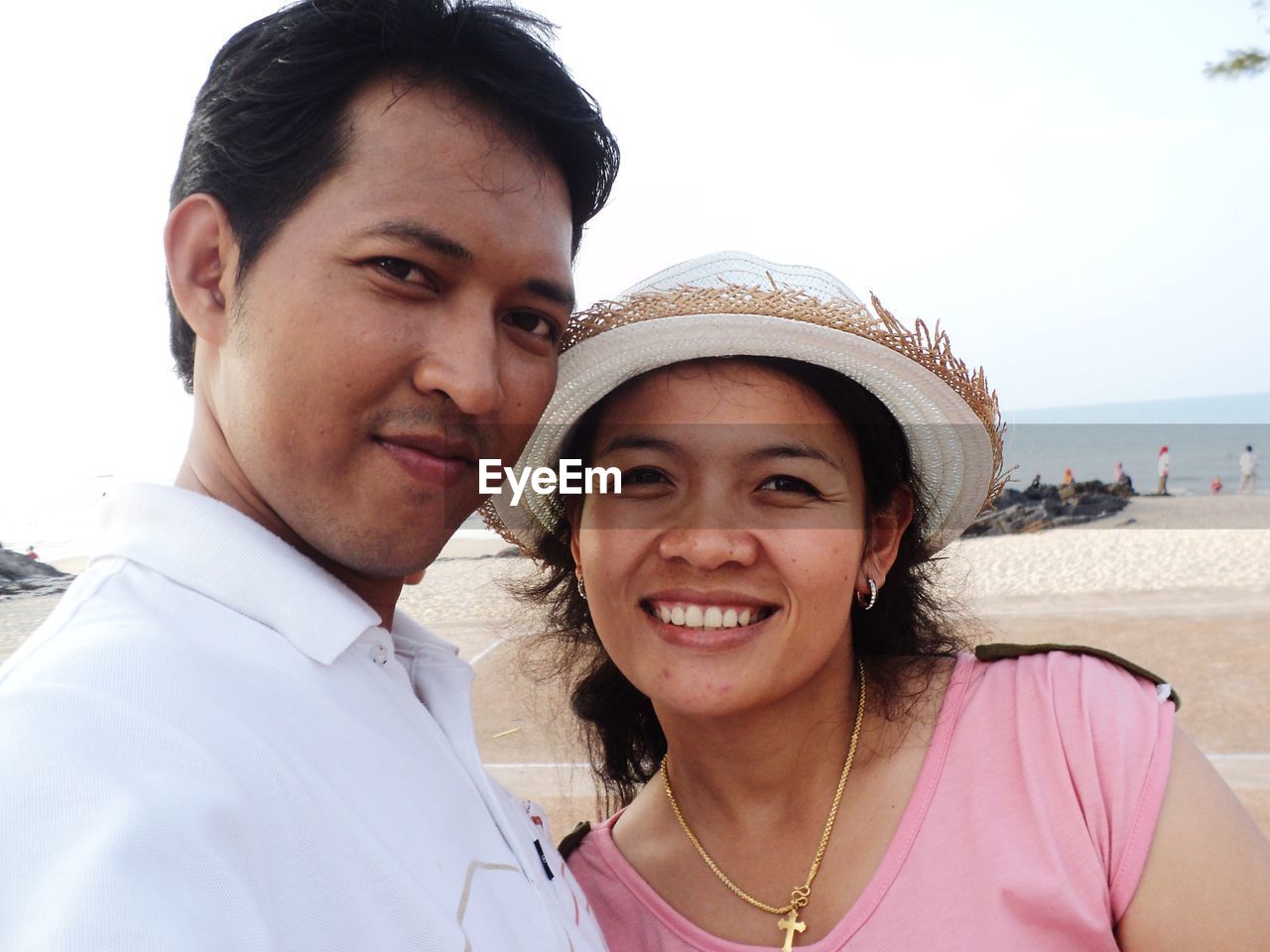 Portrait of smiling couple at beach against sky