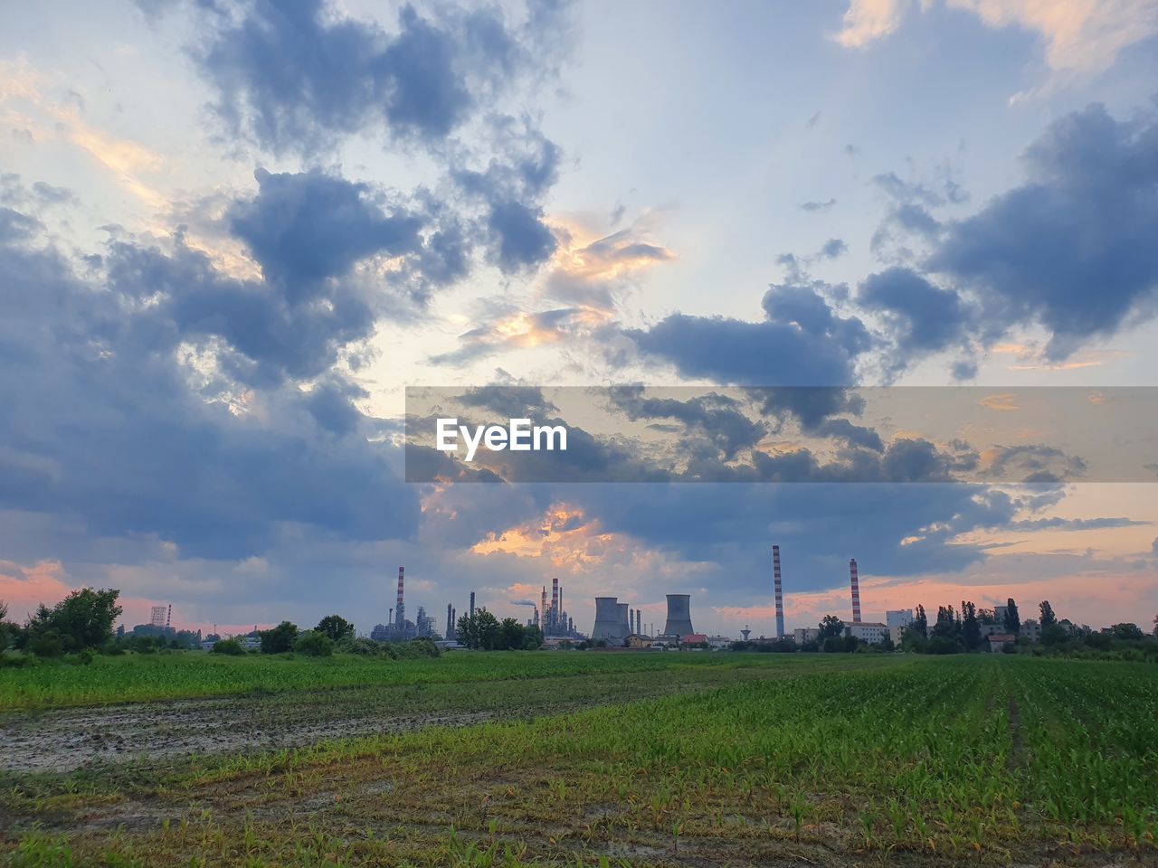 PANORAMIC VIEW OF FACTORY AGAINST SKY DURING SUNSET