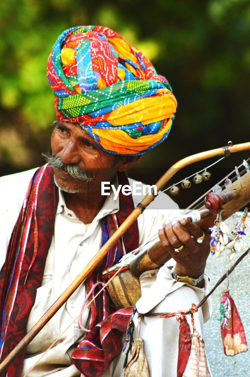 CLOSE-UP OF MAN WEARING MULTI COLORED HAND