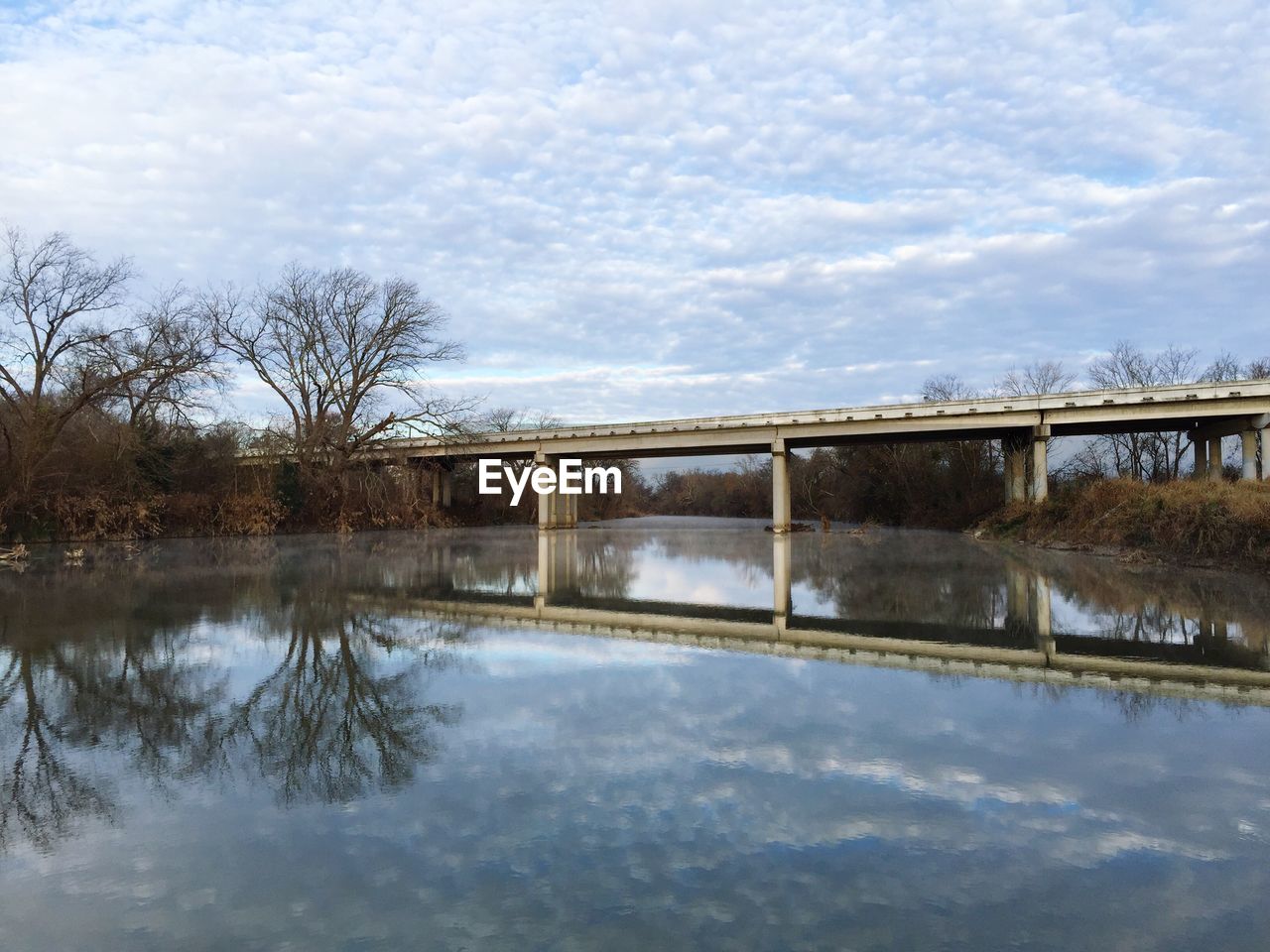 Bridge over river against cloudy sky