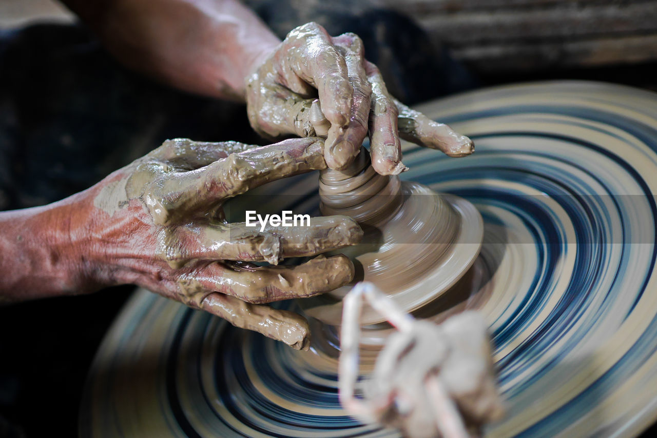 Midsection of man working on pottery wheel