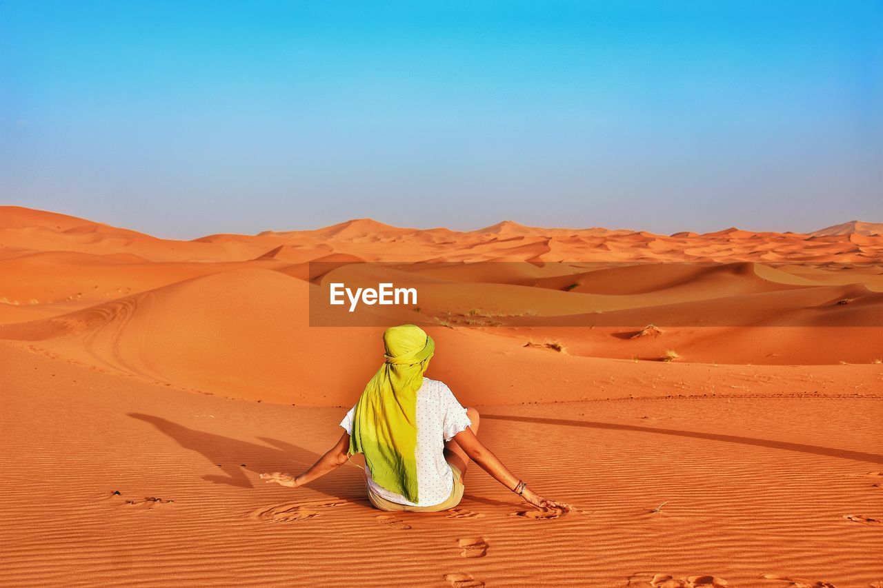 Rear vie of woman sitting at desert