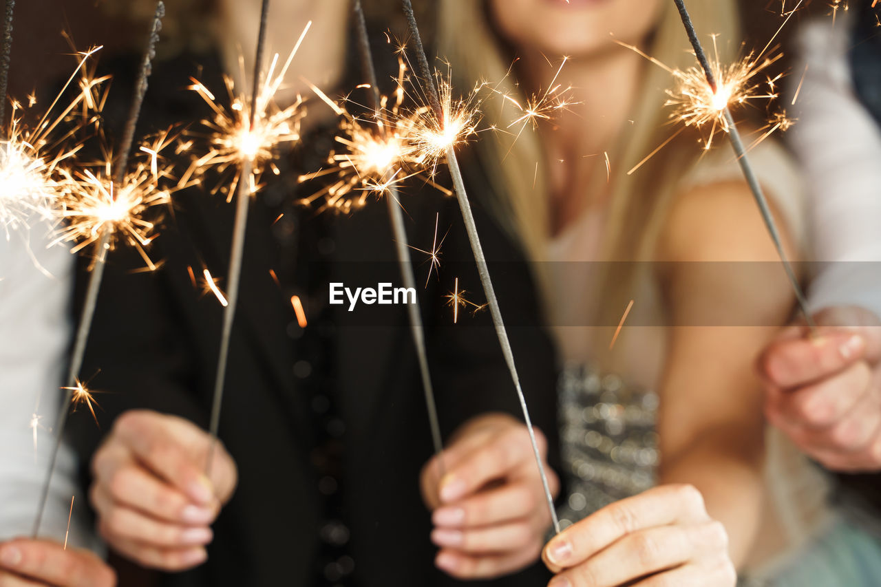 Midsection of woman holding sparkler at night