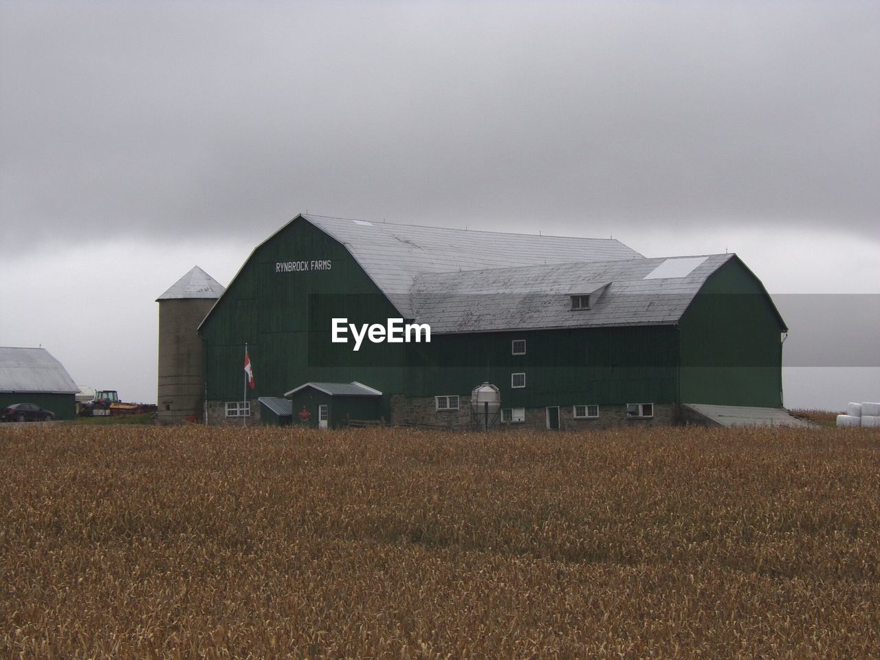 Barn on field by buildings against sky