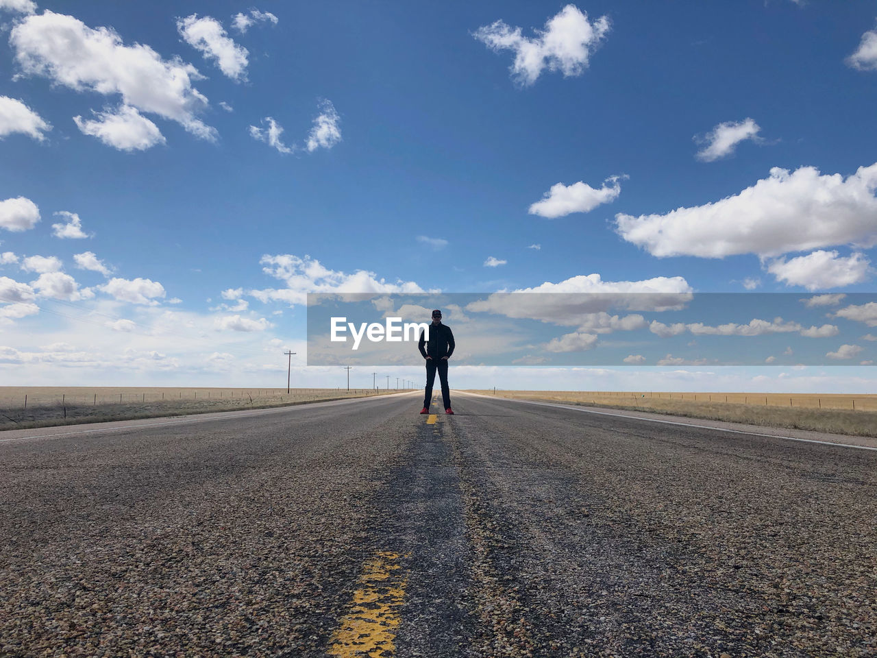 Front view of man standing on road against sky