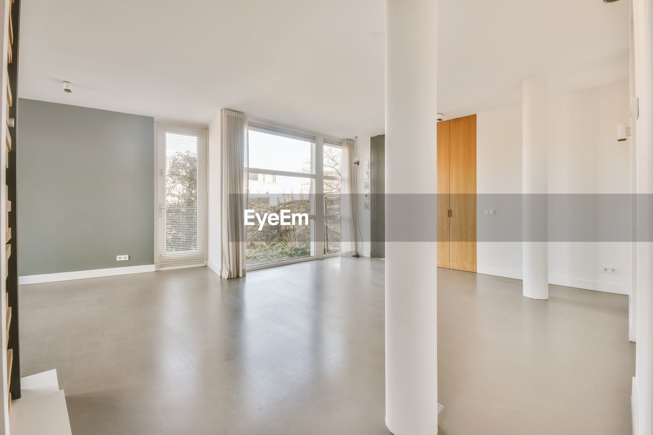 Spacious empty unfurnished room with grey wall in modern house in daylight