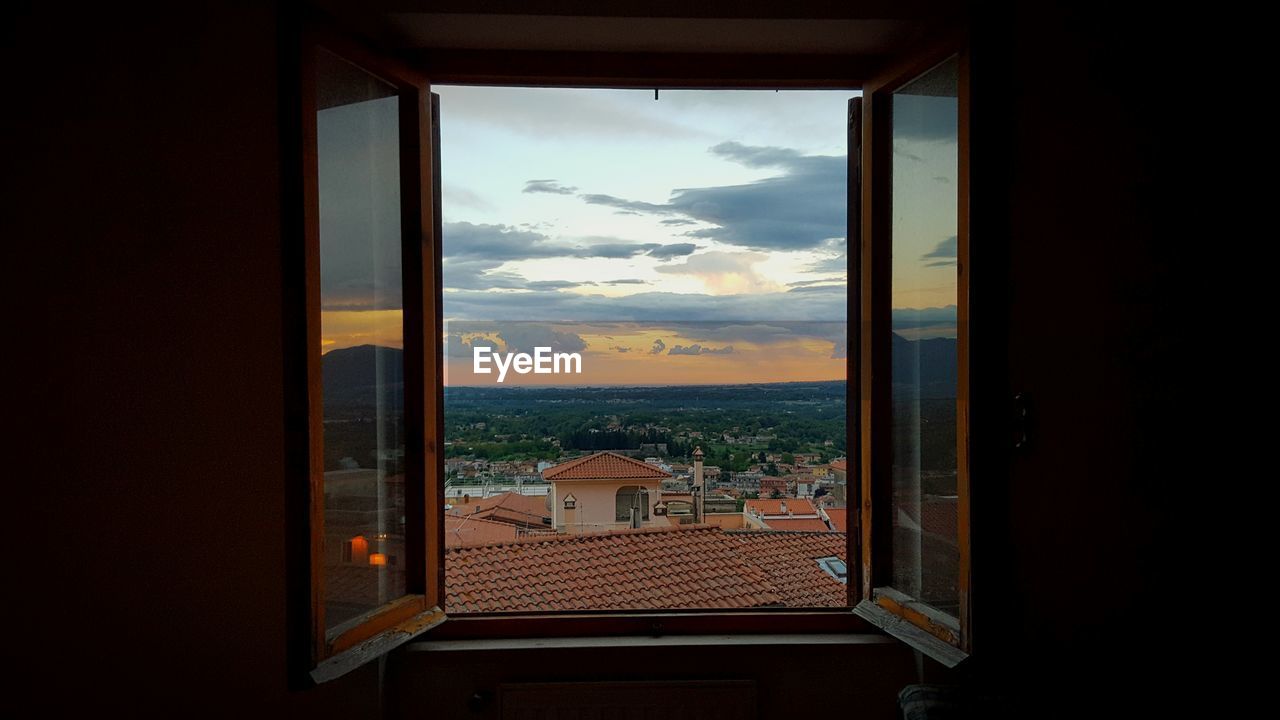 Cityscape seen through window during sunset