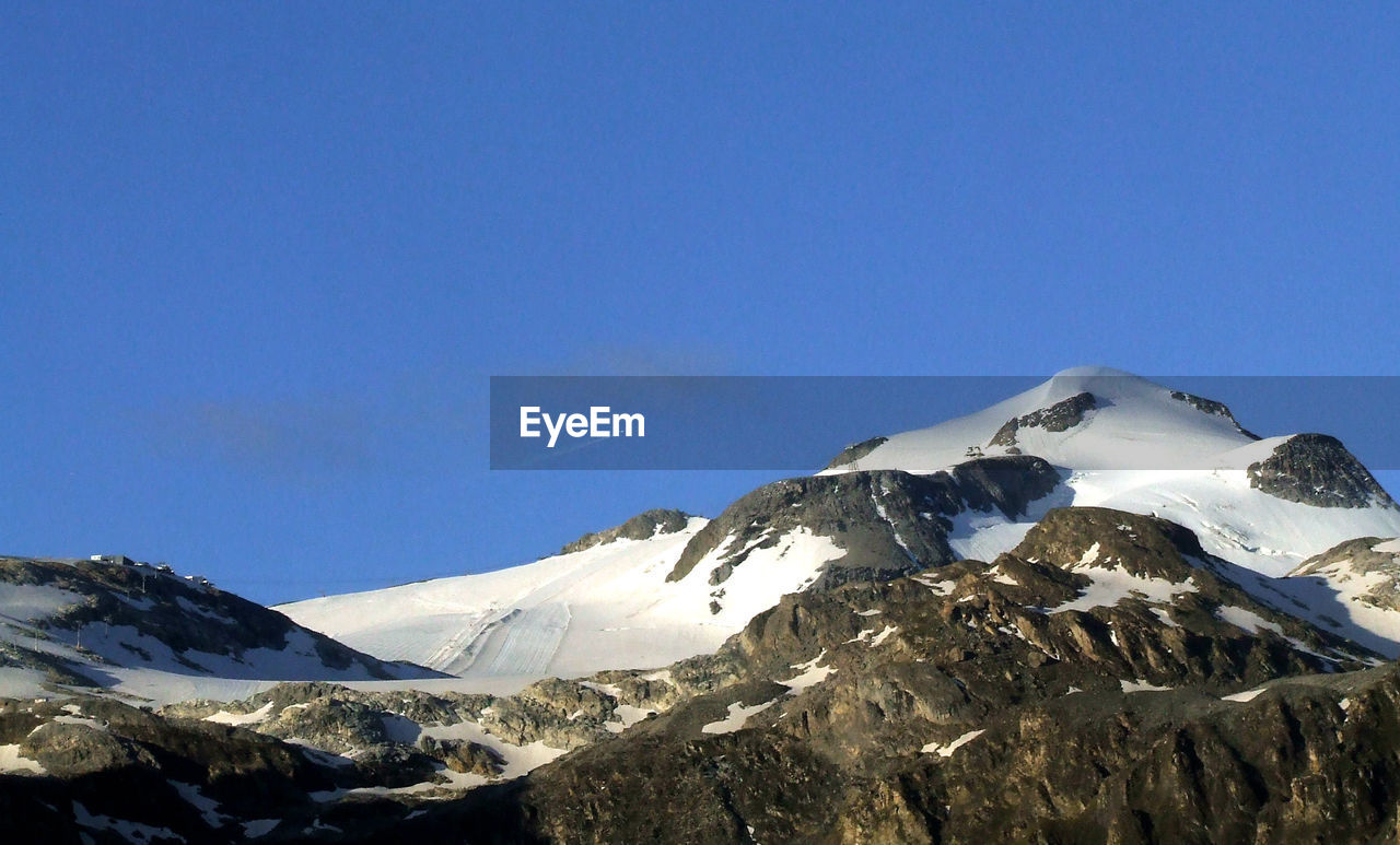 Scenic view of snowcapped mountains against clear blue sky