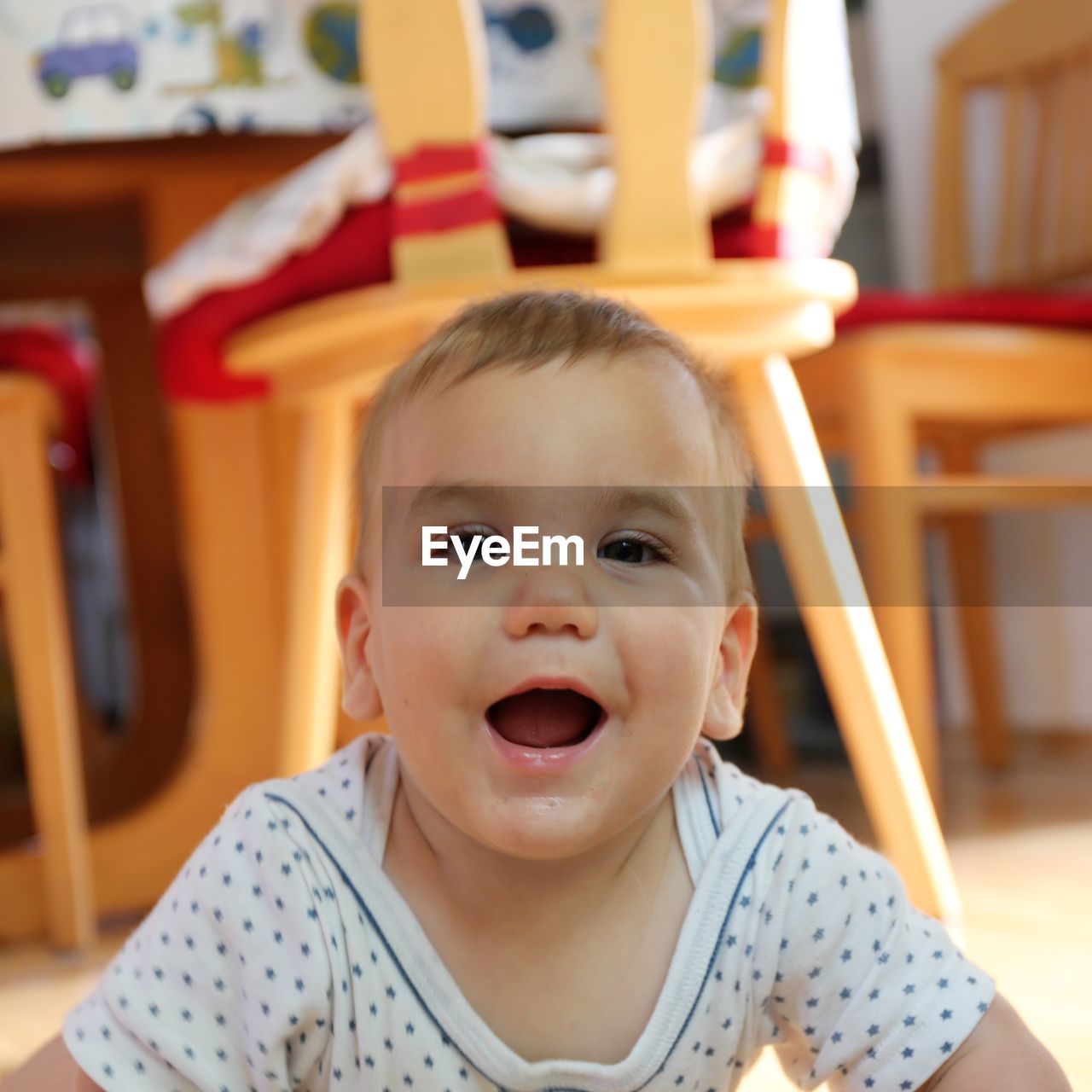 Portrait of cute cheerful baby boy lying on floor at home