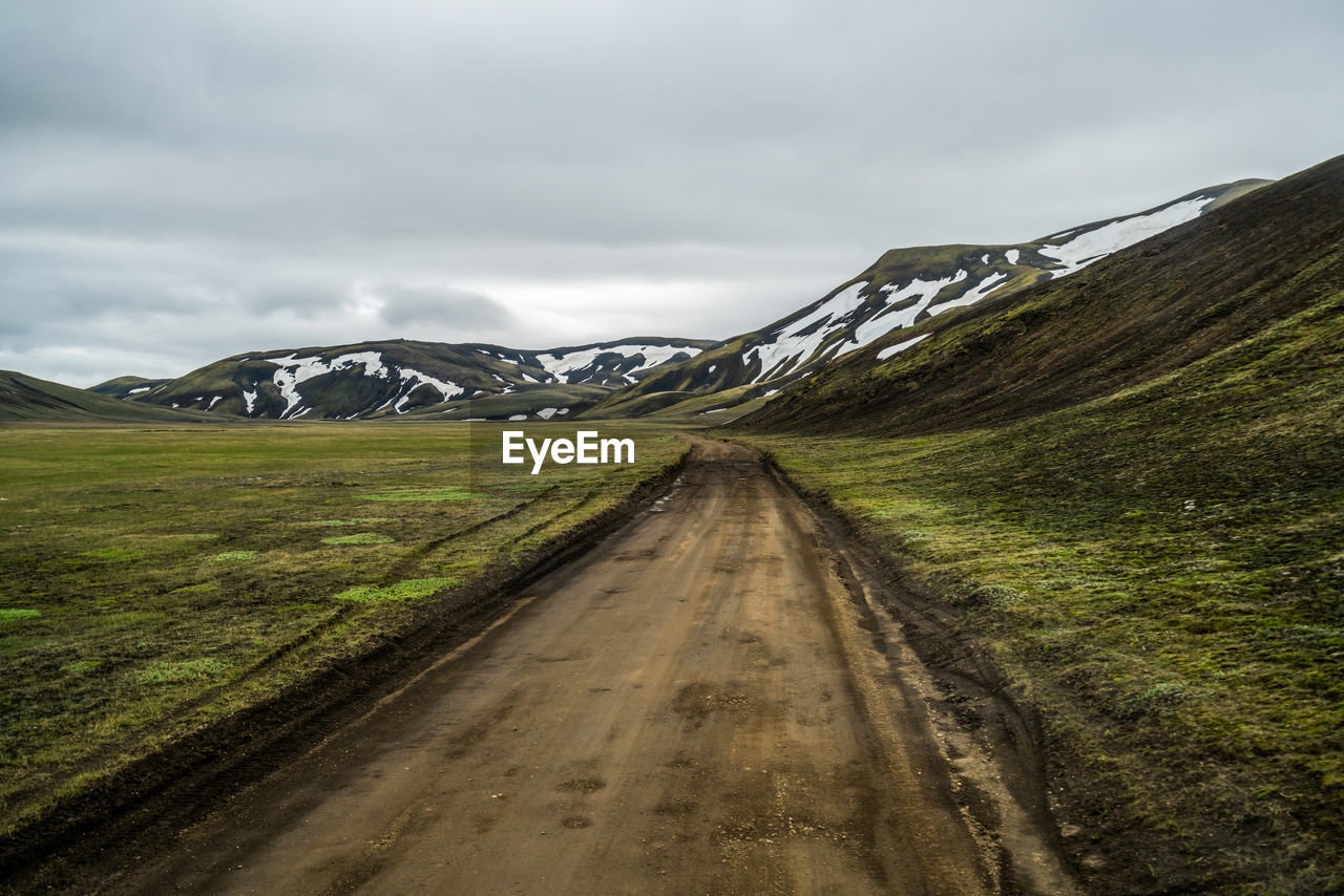 Road leading towards mountains against sky