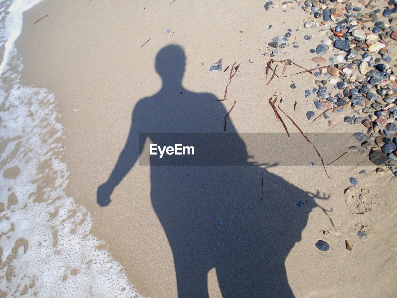 SHADOW OF PERSON ON SAND AT BEACH