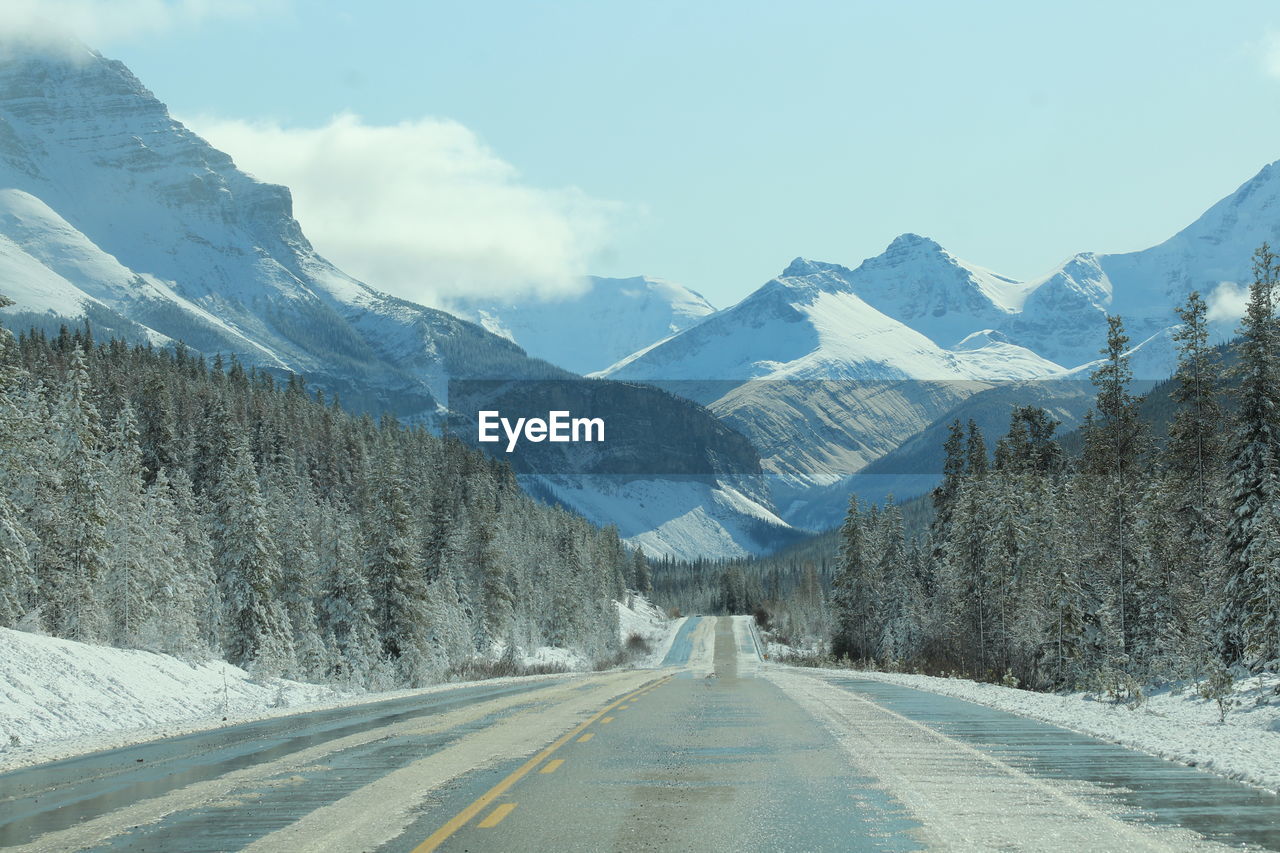 Road amidst snowcapped mountains against sky