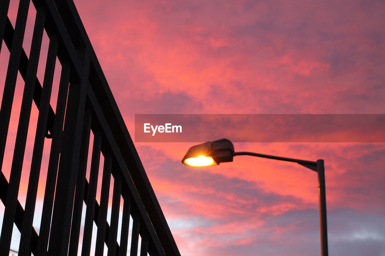 Low angle view of illuminated street light against orange sky