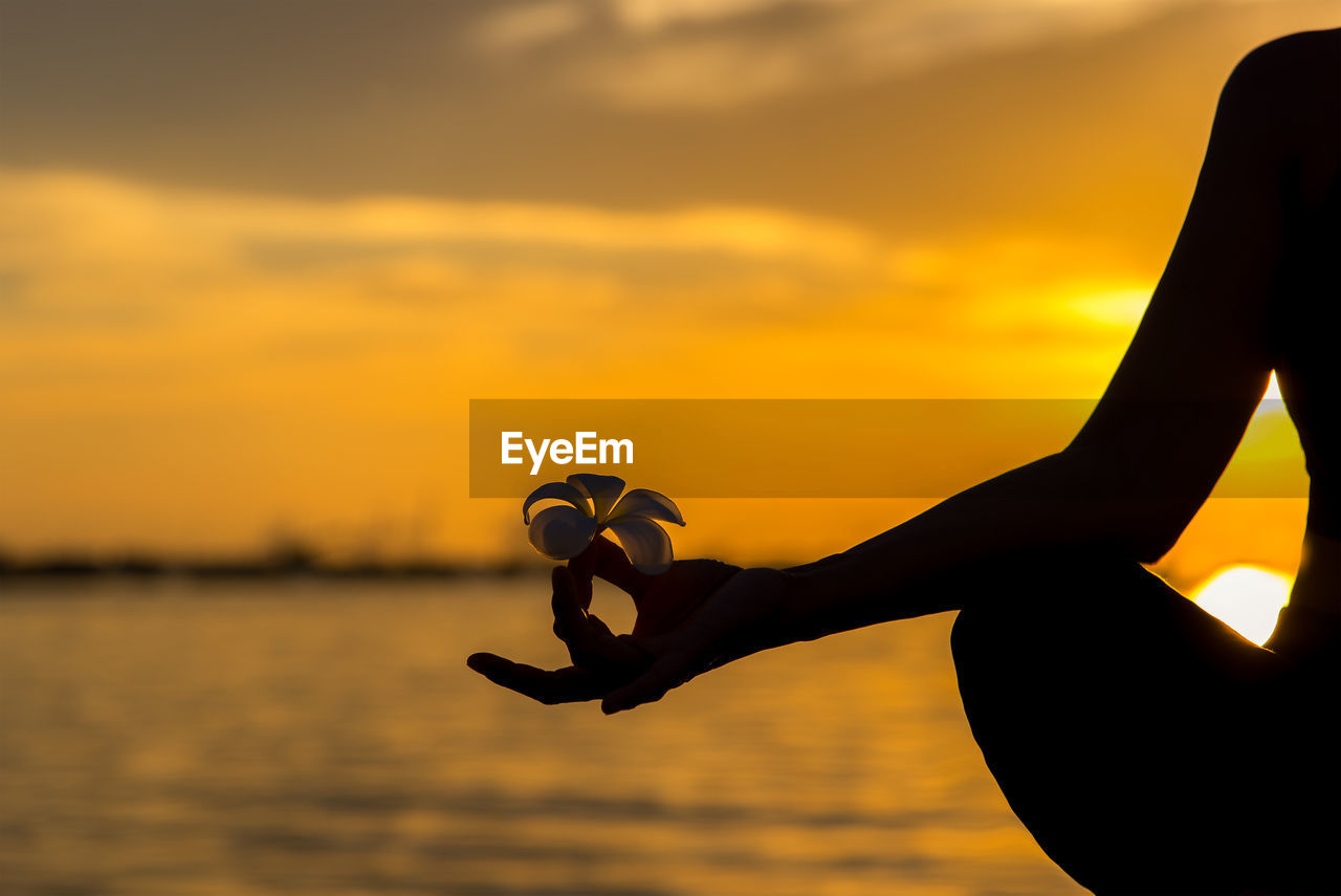 SILHOUETTE MAN HOLDING ORANGE AGAINST SKY DURING SUNSET