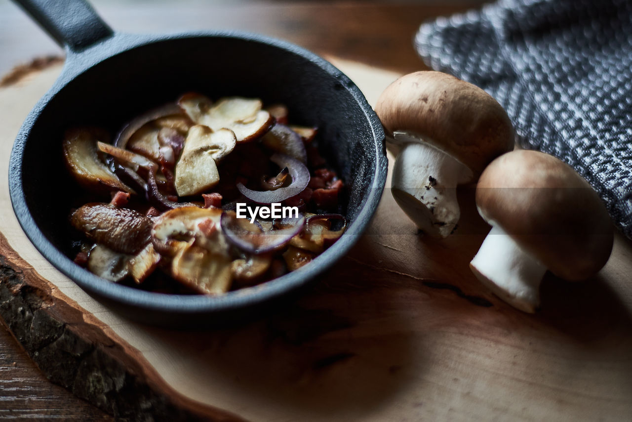 food, food and drink, healthy eating, wood, dish, kitchen utensil, freshness, indoors, wellbeing, no people, produce, vegetable, pan, household equipment, high angle view, frying pan, mushroom, close-up, cooking pan, ingredient, studio shot, table, meal, spice, edible mushroom, rustic