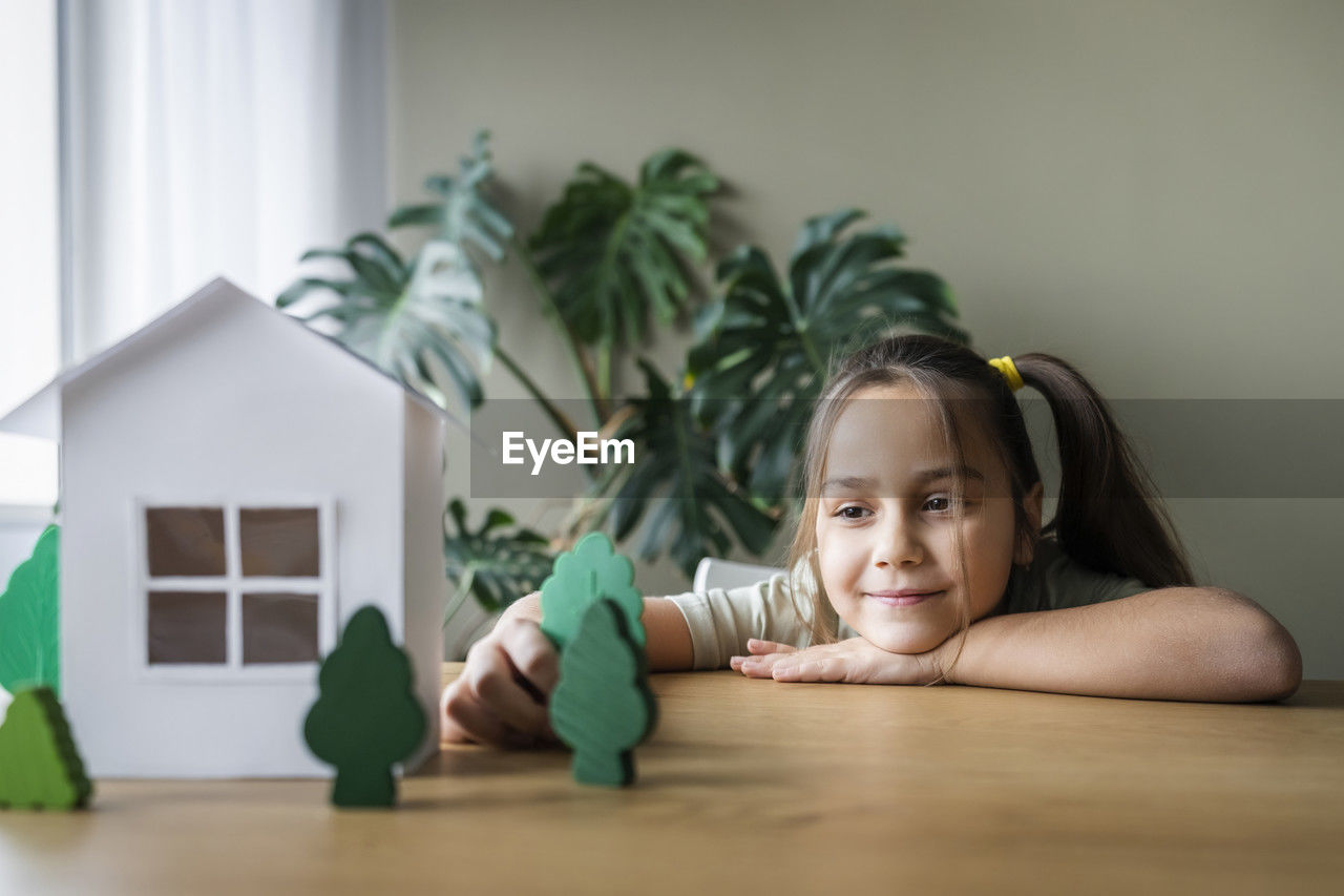 Girl playing with tree models on table at home