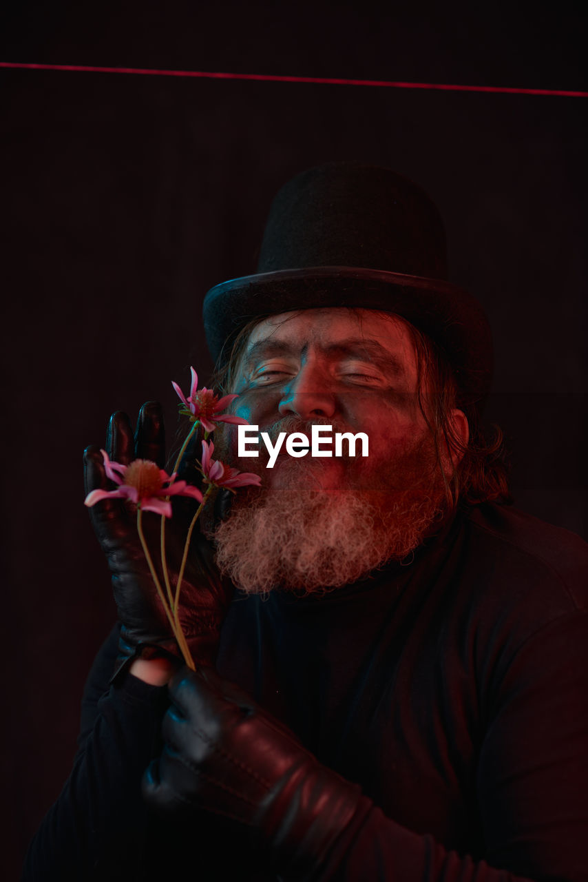 adult, one person, facial hair, men, red, beard, portrait, hat, performing arts, clothing, black background, entertainment, person, darkness, indoors, music, emotion, mature adult, performance, studio shot, headshot, stage, dark, holding, senior adult, concert, night, human face