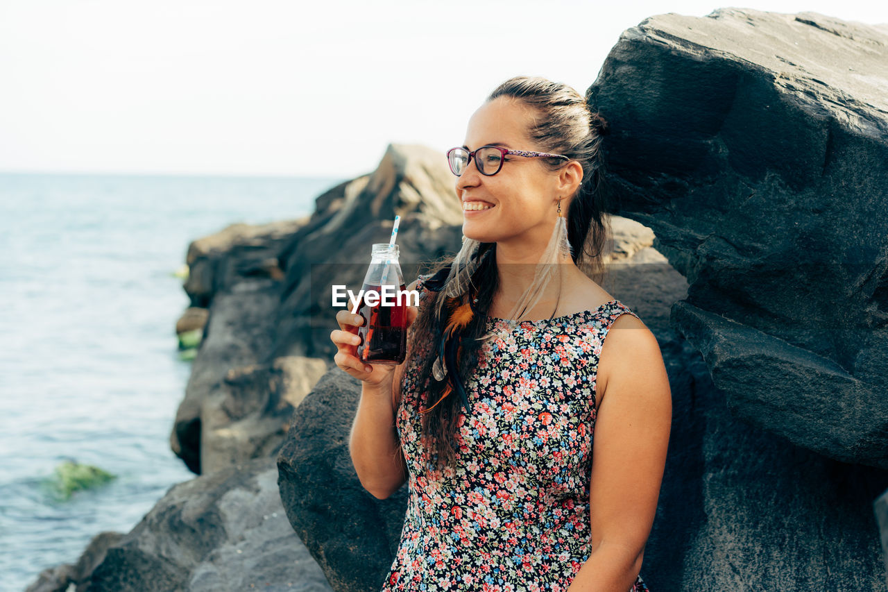 Woman looking away while drinking juice outdoors