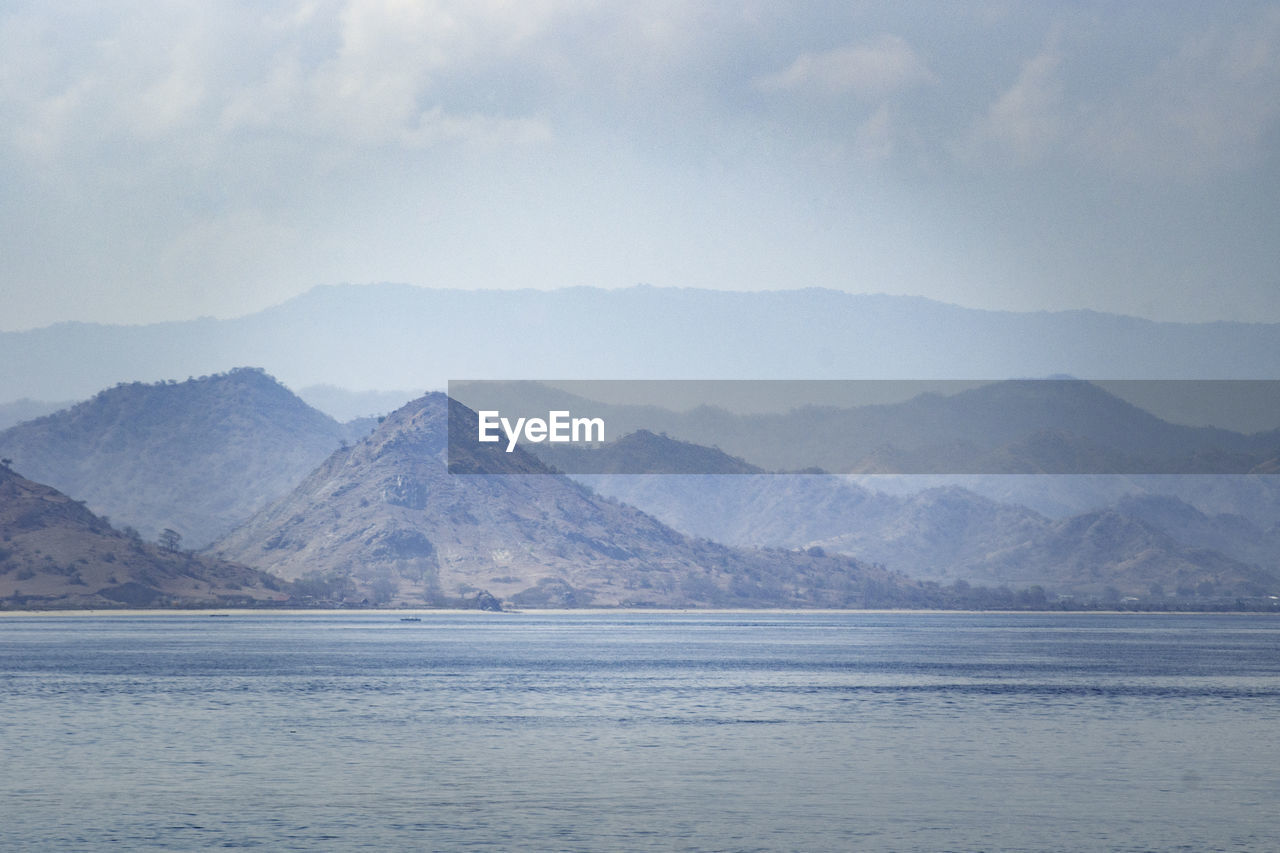 Scenic view of sea and mountains against sky