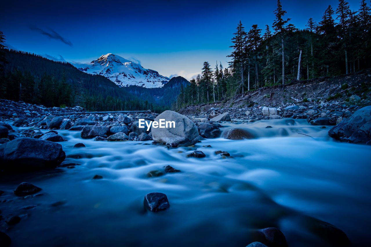 Surface level of water flowing in rocks against blue sky