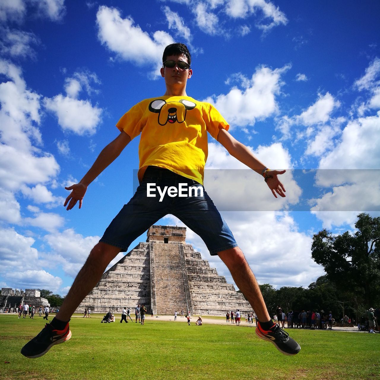 Low angle view of man jumping on field at el castillo chichen itza