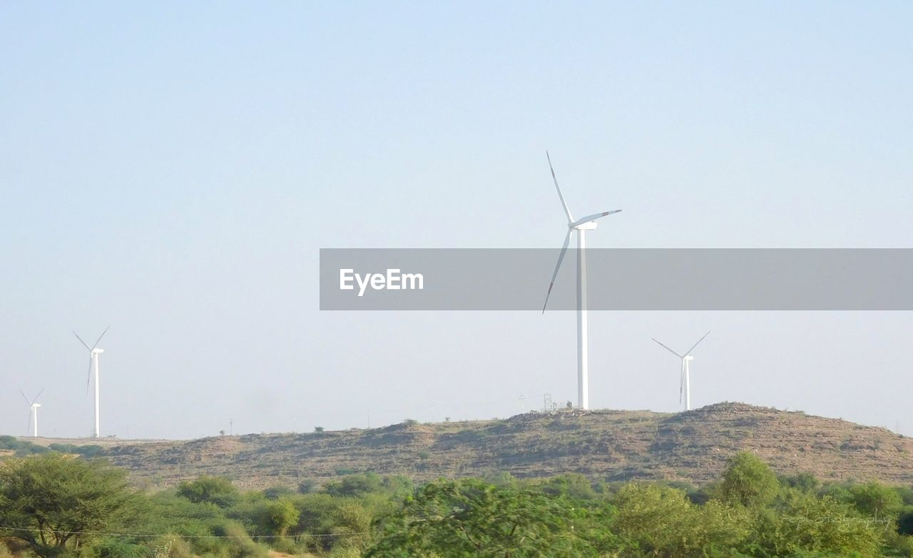 LOW ANGLE VIEW OF WINDMILLS ON FIELD AGAINST SKY