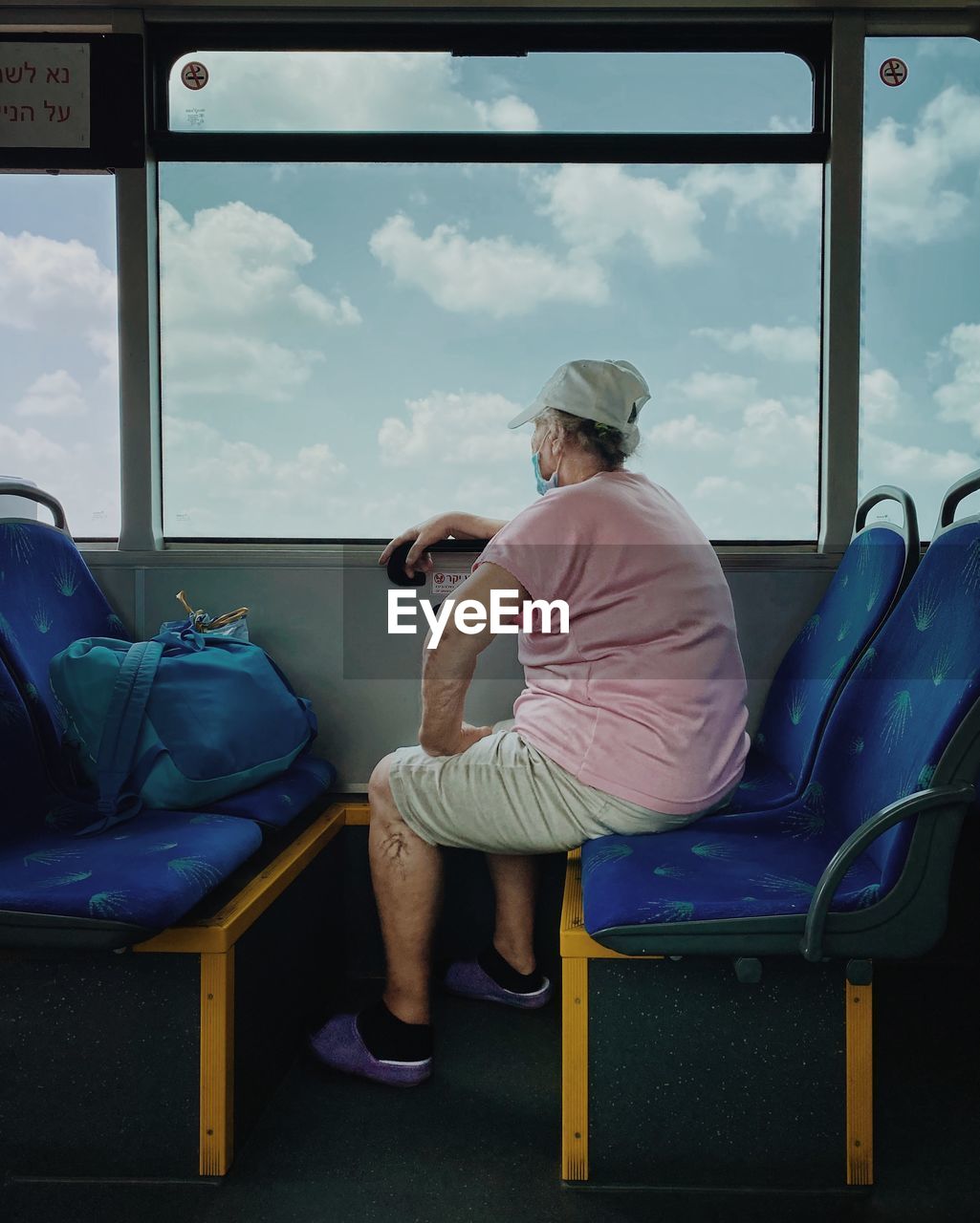 REAR VIEW OF MAN SITTING ON CHAIR AGAINST BUS