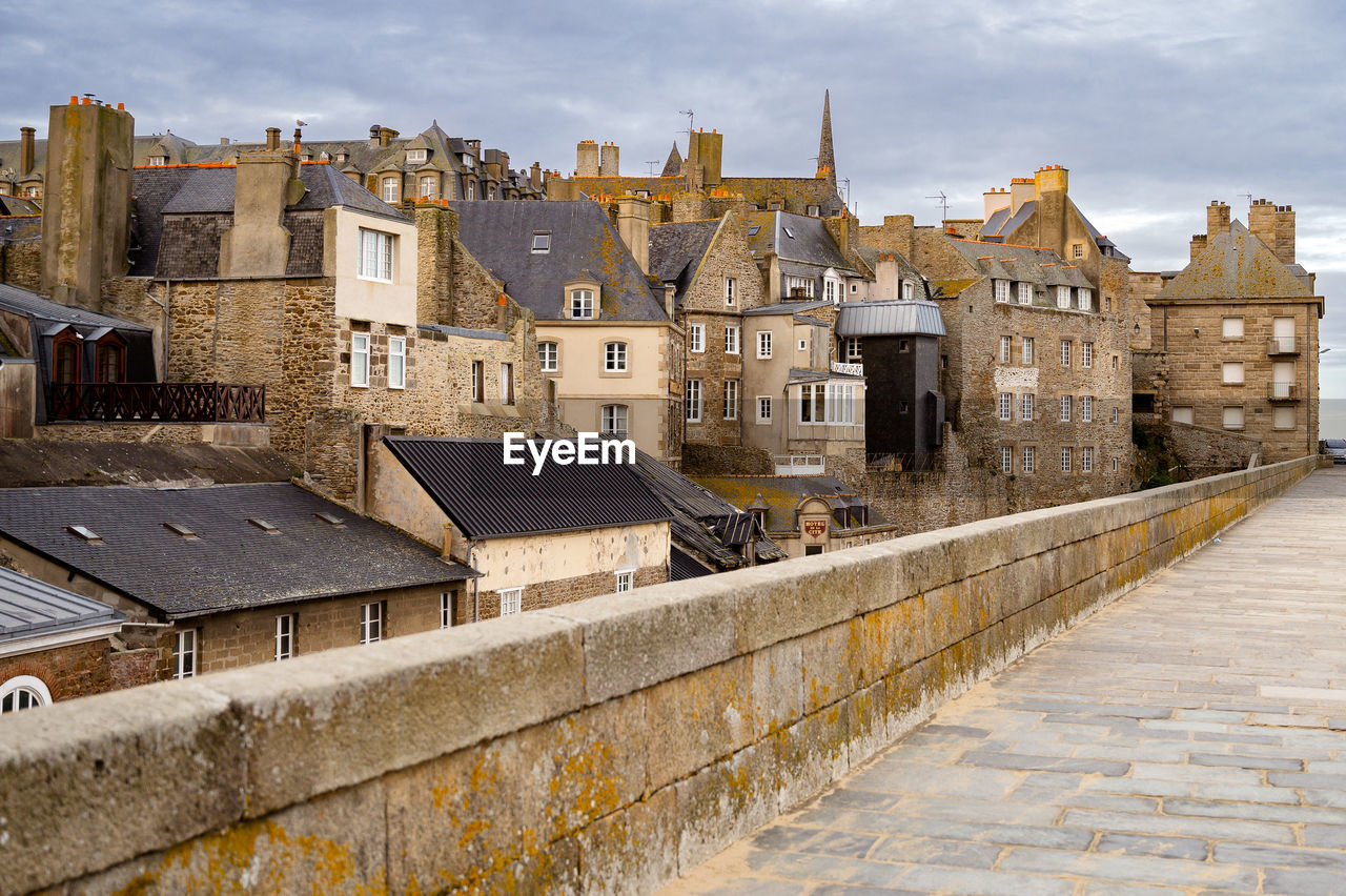 Old stone buildings in a city surrounded by medieval walls.