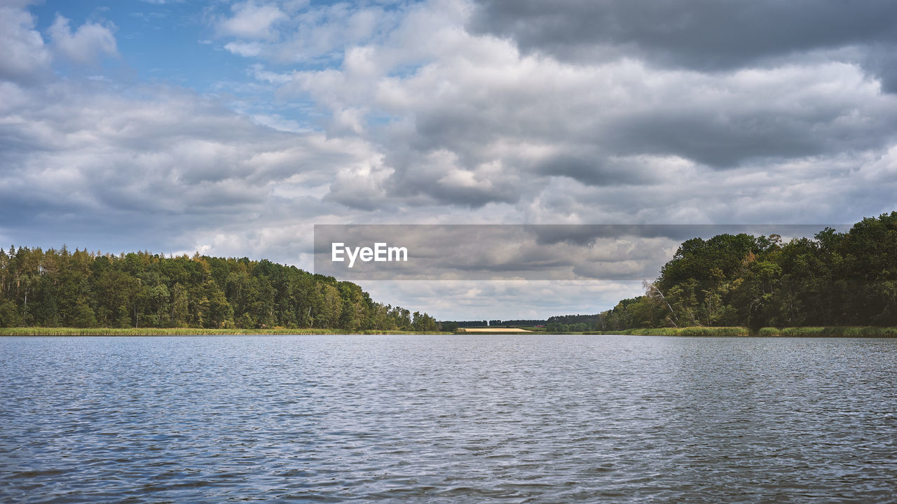 Cloudy summer weather at a lake in the middle of a dense forest.