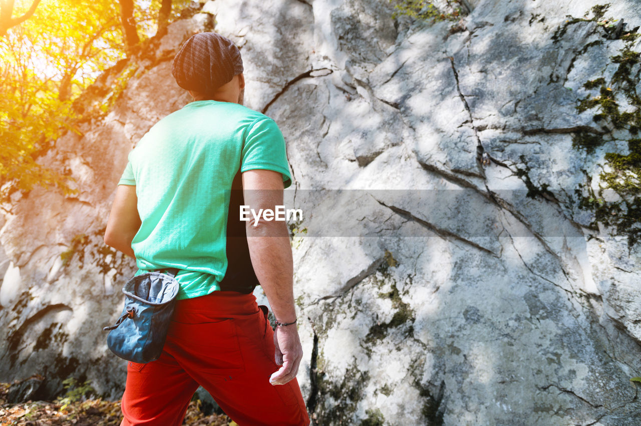 Athletic middle aged male climber stands in front of a large training rock before free mountain 