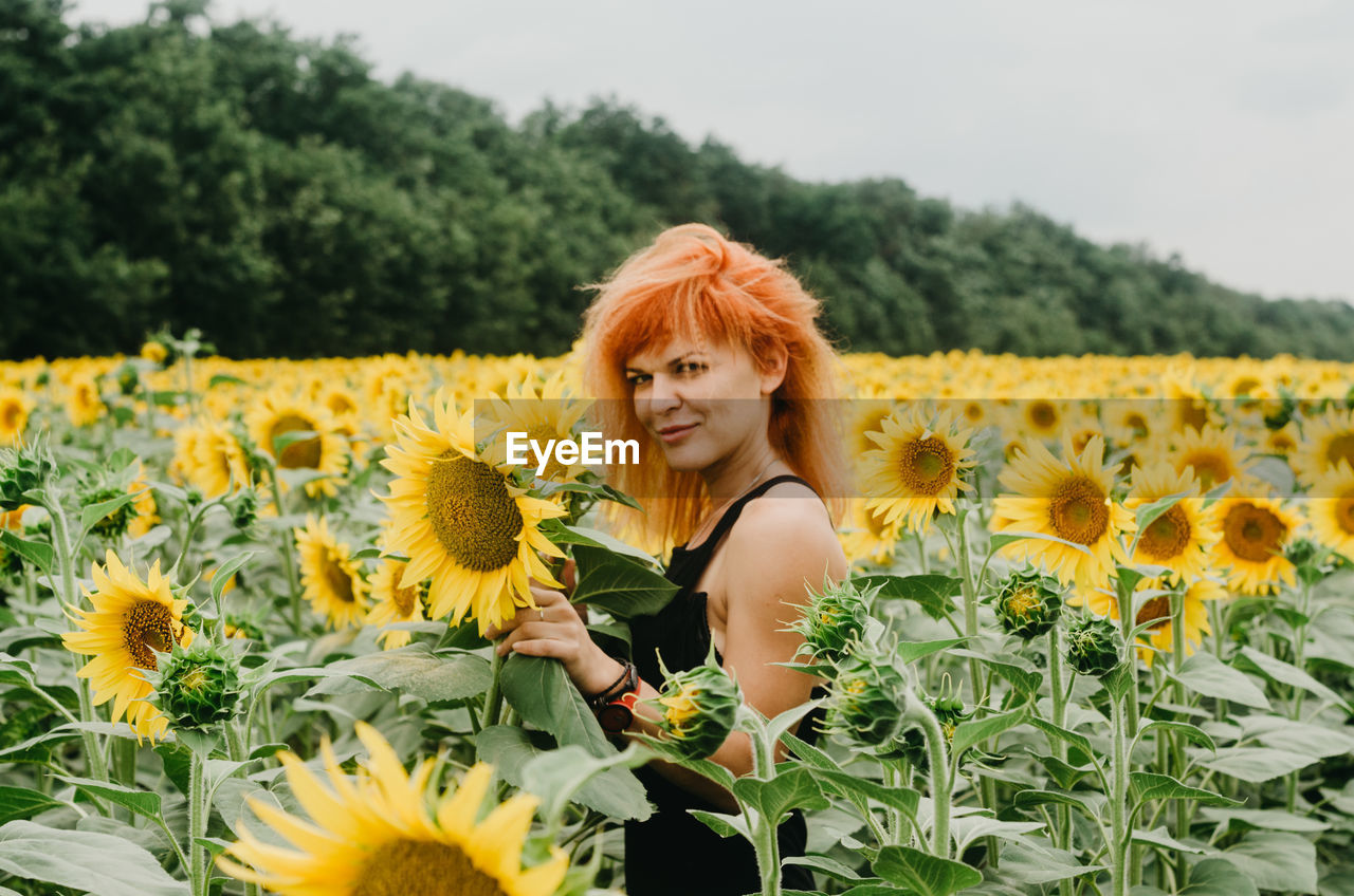Portrait of woman standing amidst sunflowers