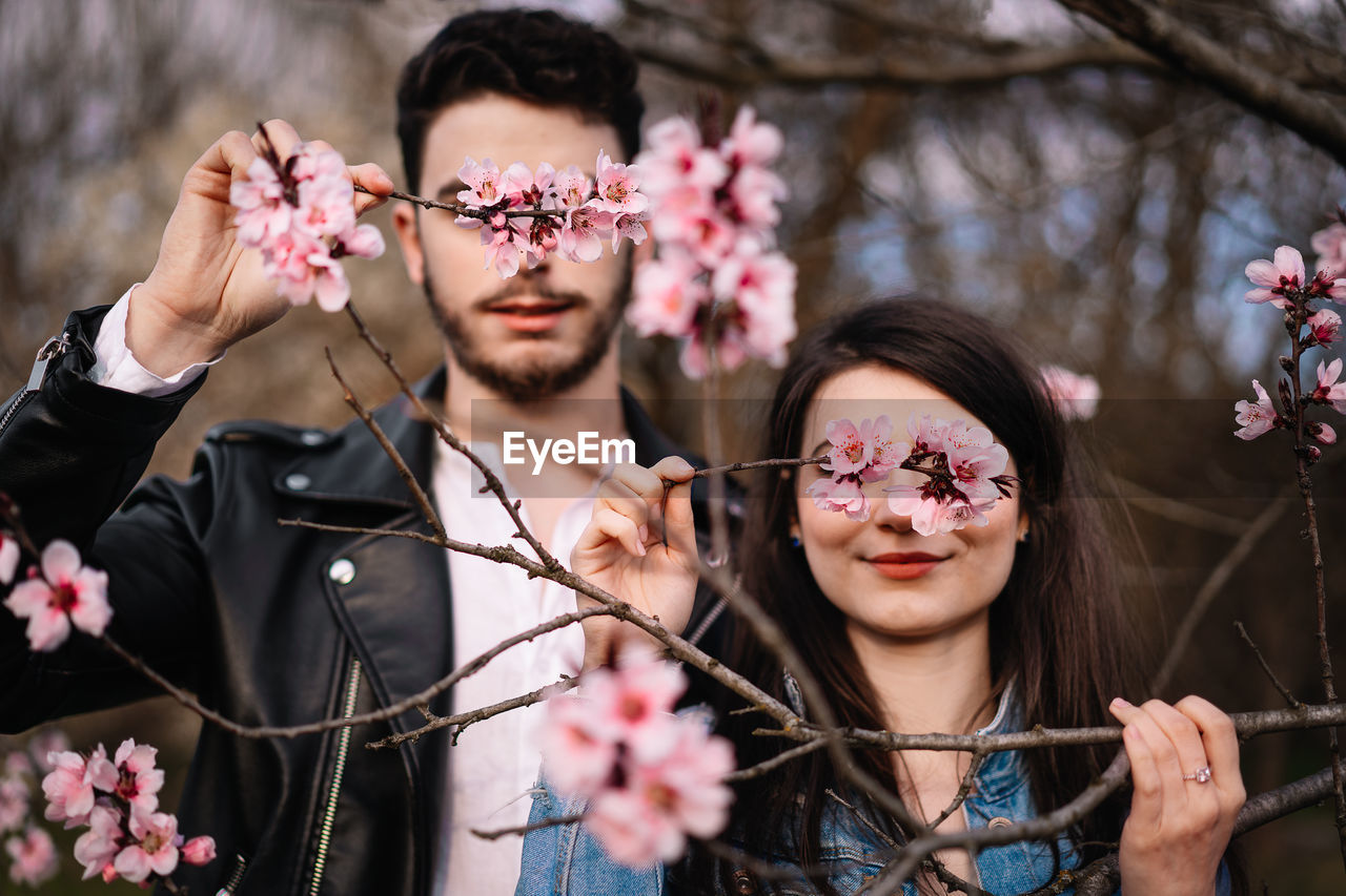 Portrait of young woman and man holding flowering plants