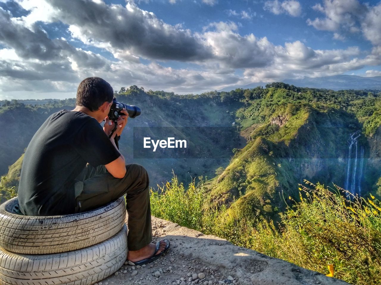 Rear view of man photographing mountain range