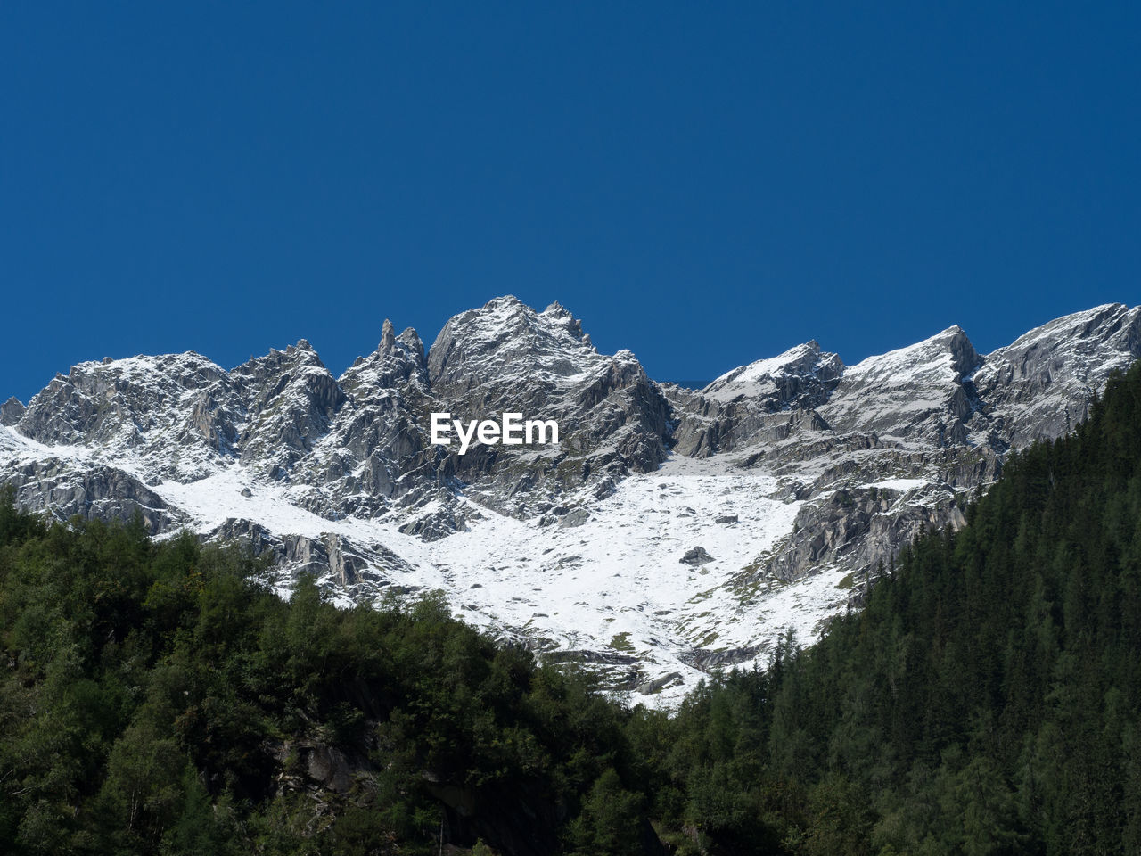 Scenic view of snowcapped mountains against clear blue sky