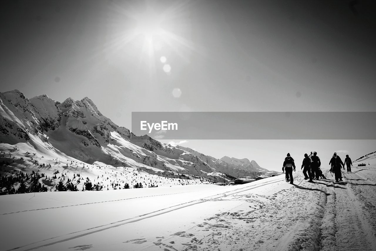 People walking on snowcapped mountain against sky