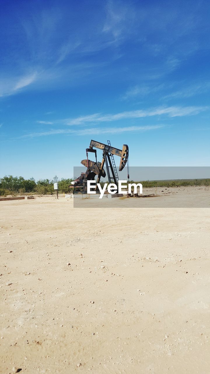 Oil drill on field against sky
