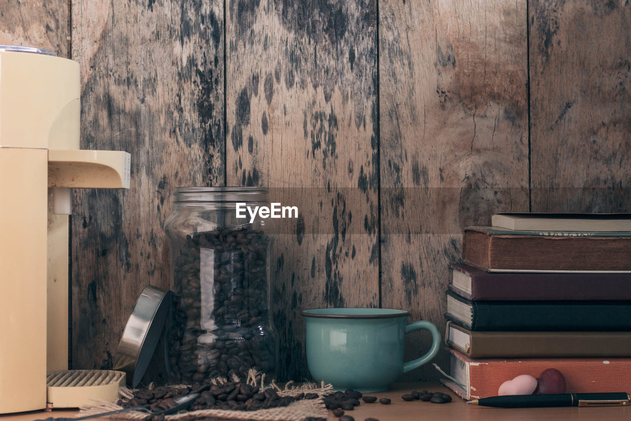 Close-up of roasted coffee beans in jar by books on table